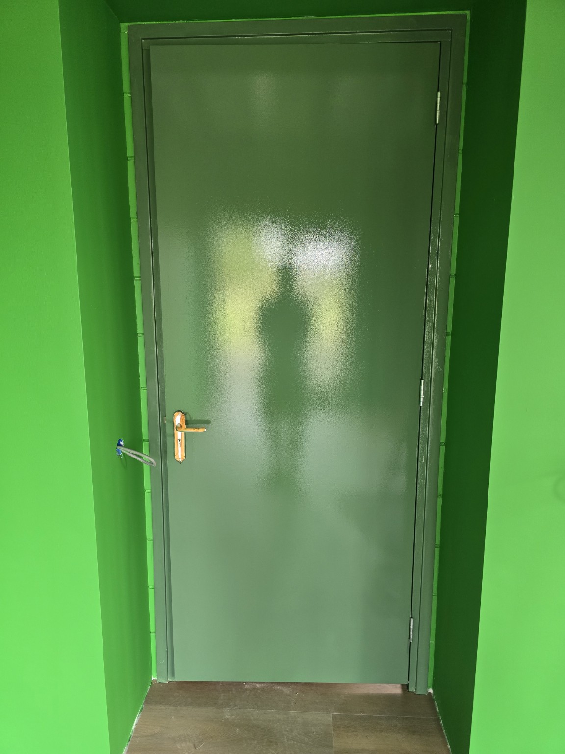 De binnendeur en het kozijn na het schilderwerk in groen, naast heldergroene wanden