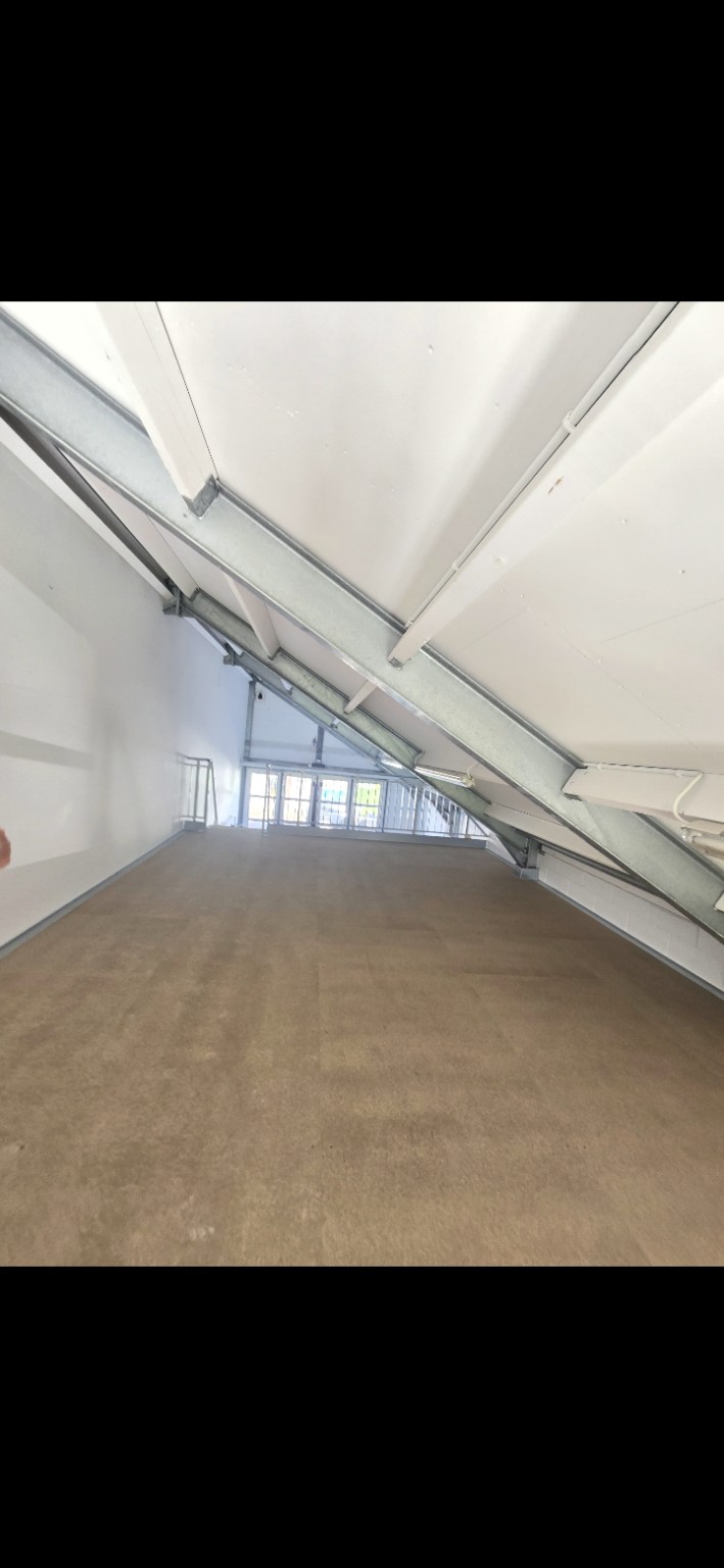 De werkruimte vóór het schilderwerk met witte wanden, een wit schuin plafond en stalen balken